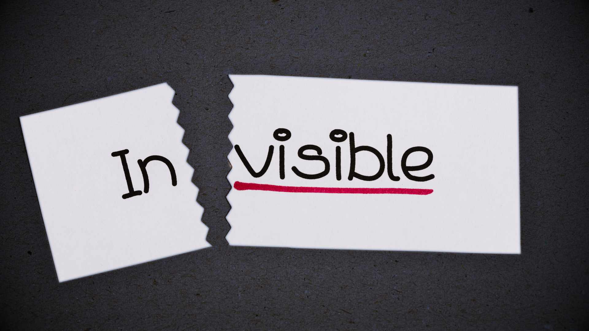 Deux morceaux de papier déchirés avec les mots "In" et "visible" qui forment le mot "invisible", symbole de l'importance du SEO pour devenir visible sur Google