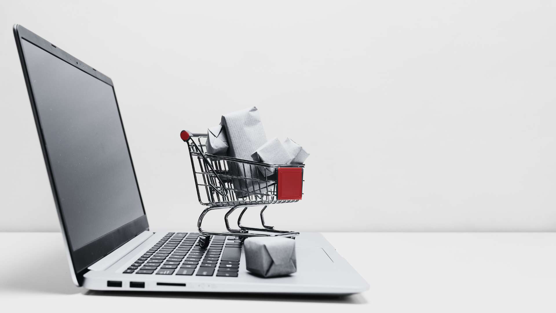 Ordinateur portable avec un mini caddie rempli de paquets, pour illustrer la simplicité de création d'une boutique en ligne avec WooCommerce