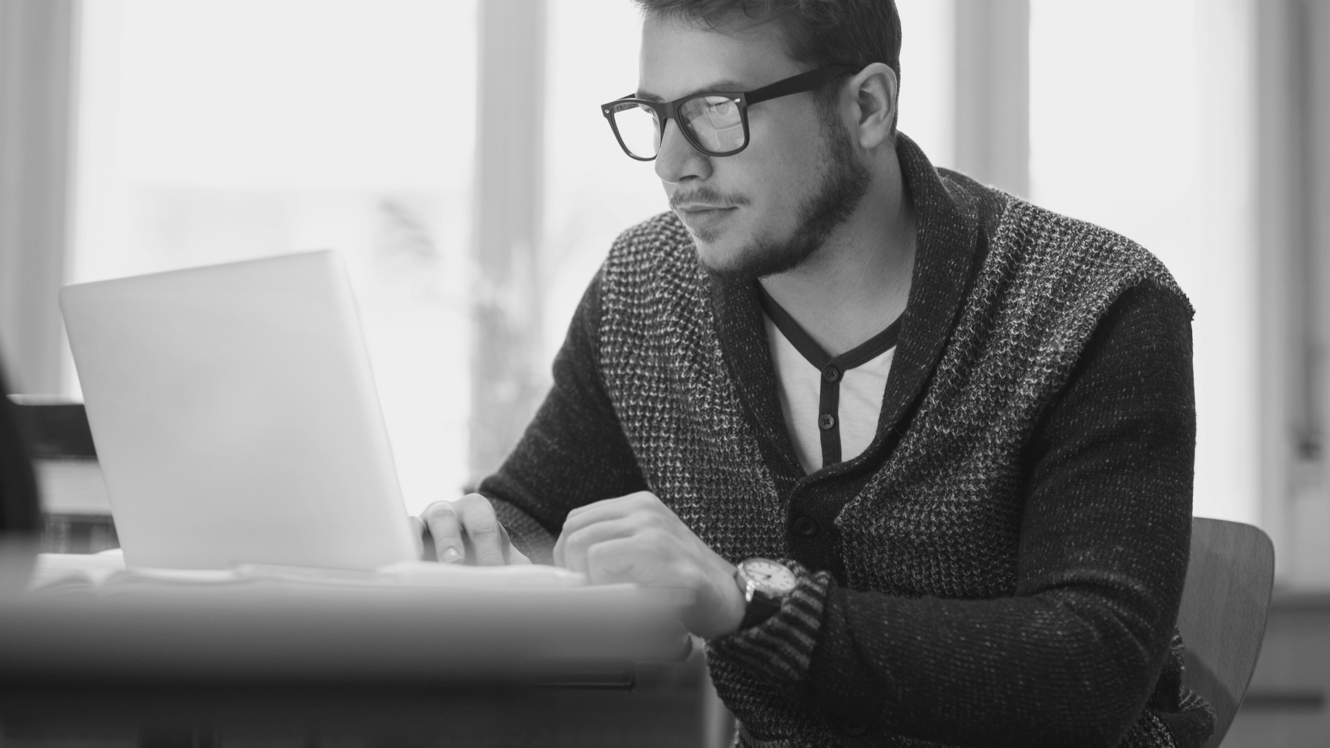 Homme assis devant un ordinateur portable, préoccupé par la sécurité dans l'hébergement web.