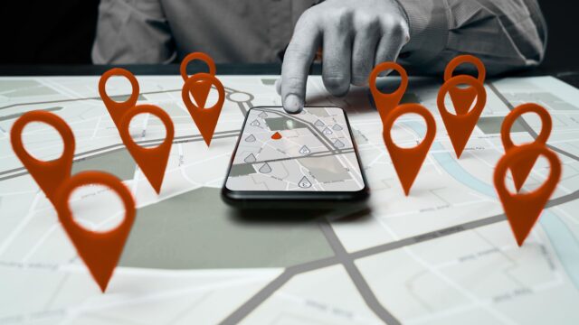 Carte interactive avec des repères géographiques rouges et un smartphone qui illustrent une stratégie de référencement local