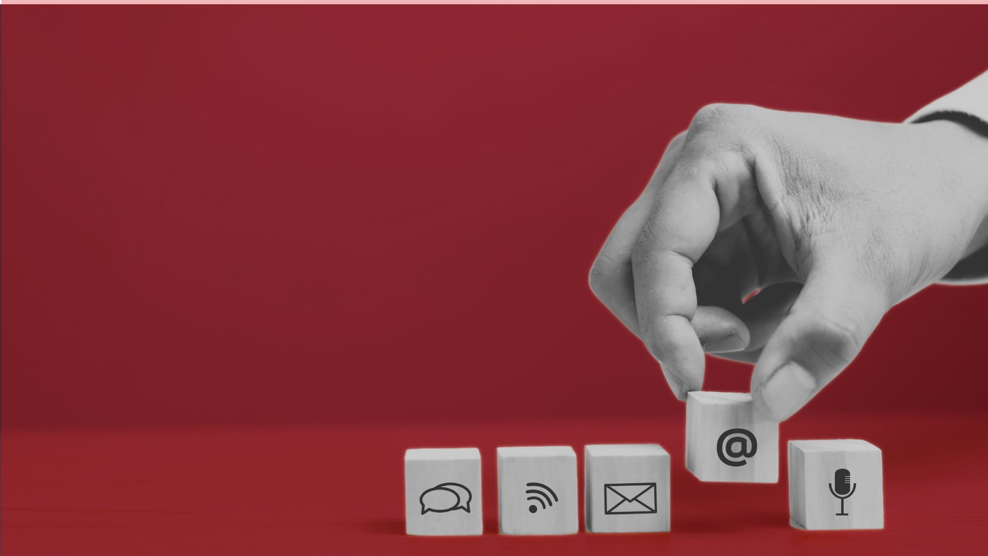 Une main dépose un cube avec une icône arobase parmi d'autres symboles de communication, pour illustrer les besoins numériques des collectivités